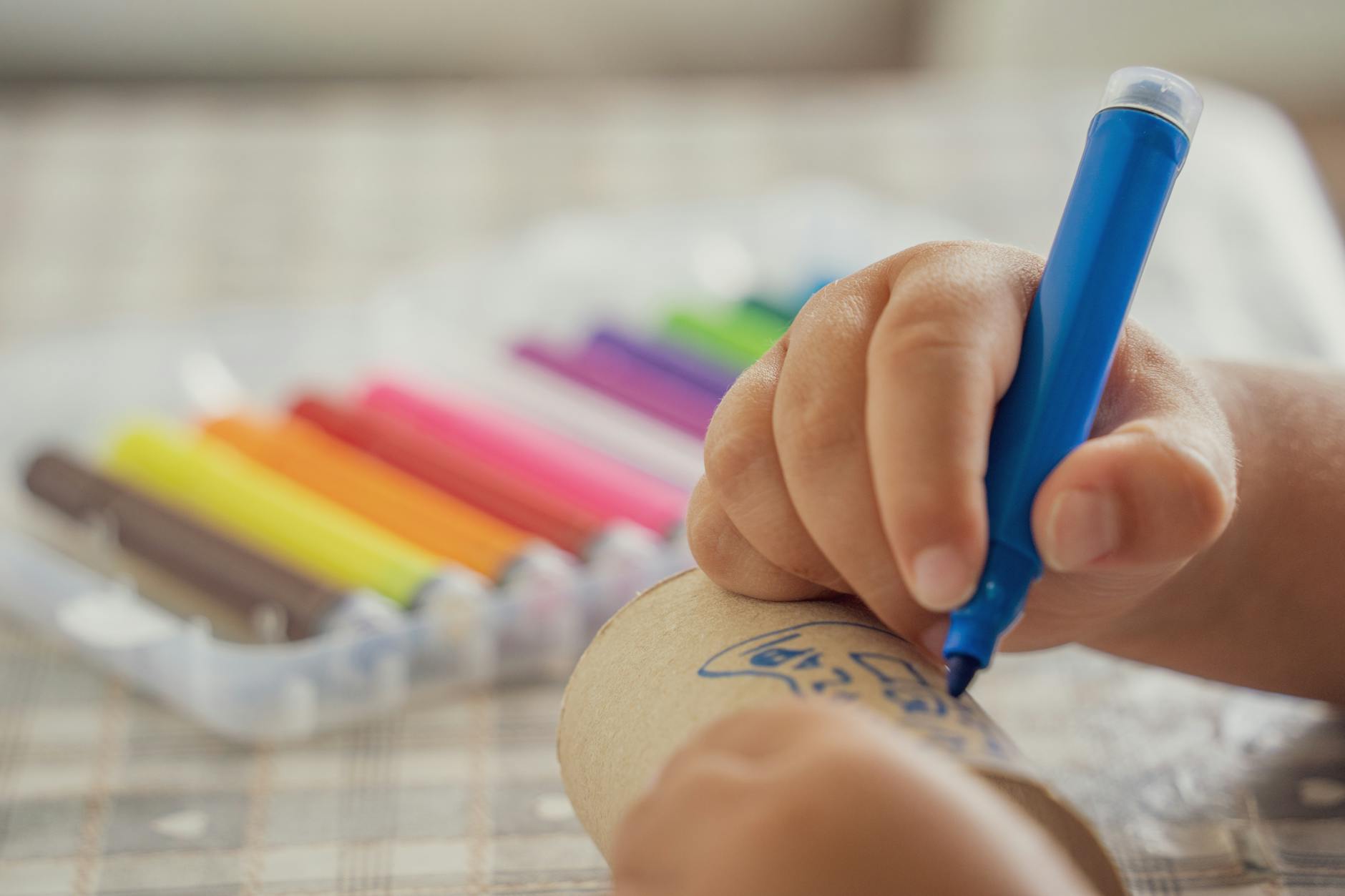 child drawing with colorful markers on paper